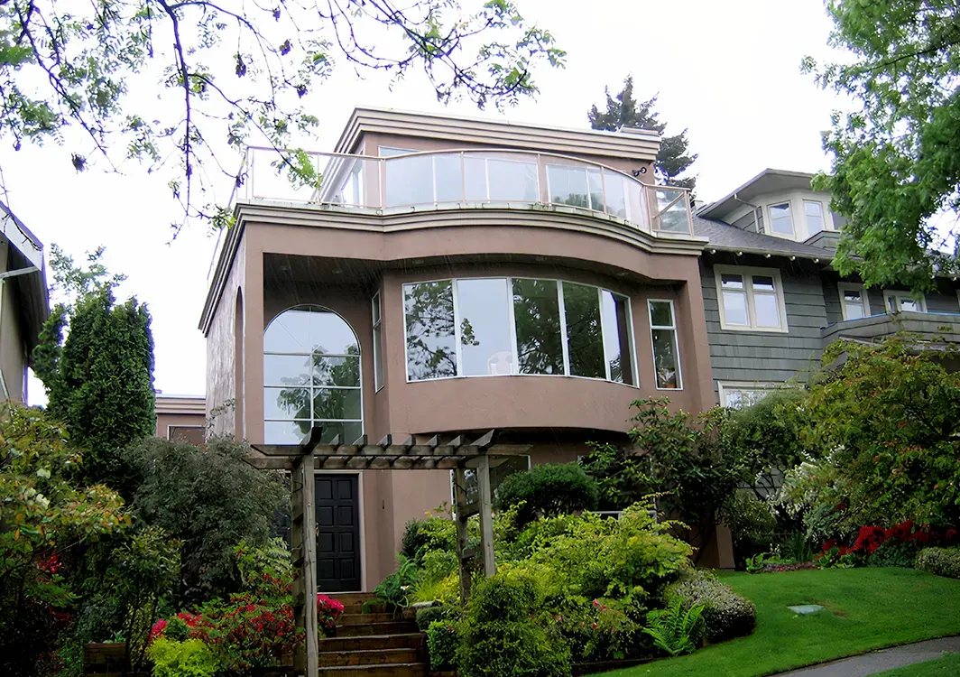Updated exterior painting on a modern Vancouver home with curved façade and large windows framed by lush gardens.