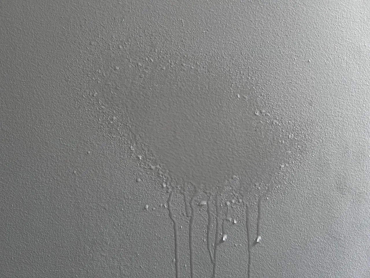 A wet stain on the beige wall.
