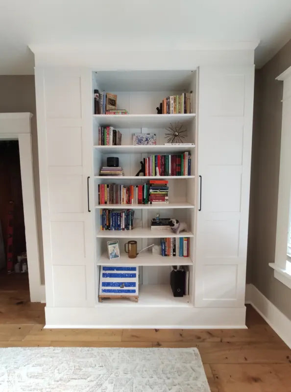 White bookshelf with doors, filled with colorful books; client finds top and bottom parts less appealing.