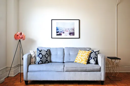 A cozy painted interior room with a grey couch in the middle.