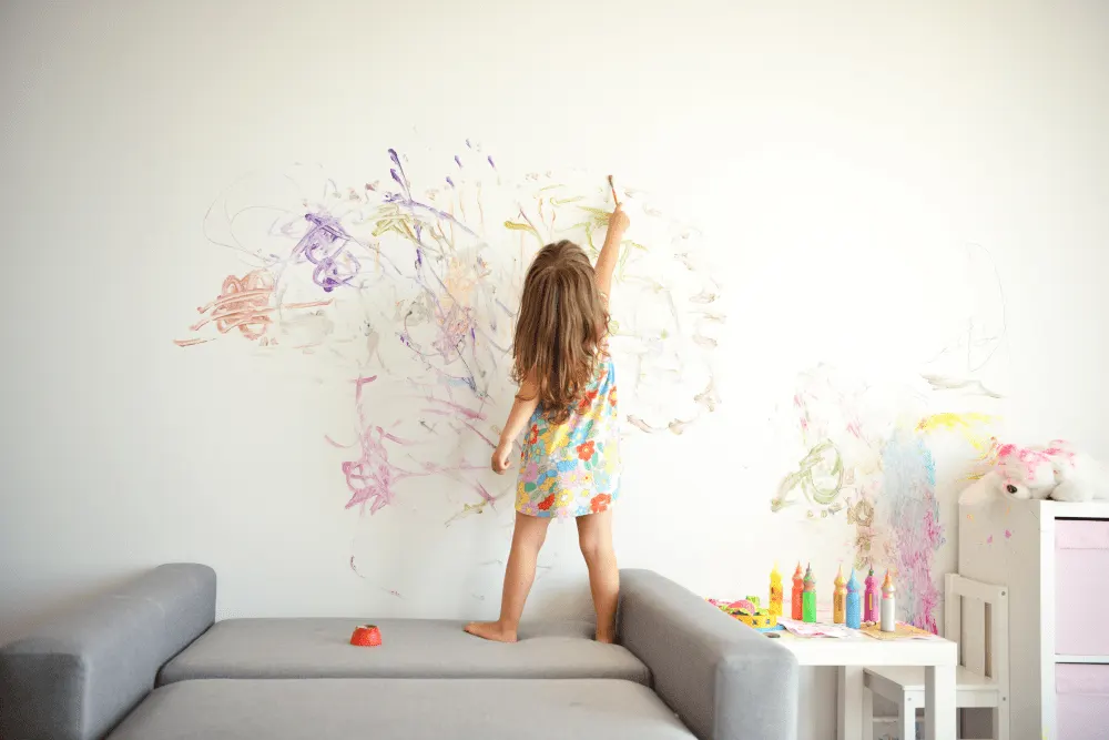 A kid is drawing on the wall.