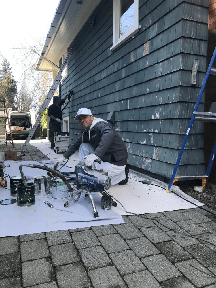 Pat Dohergy, an experienced painter from the Renaissance Solutions crew is painting a large house exterior wall.