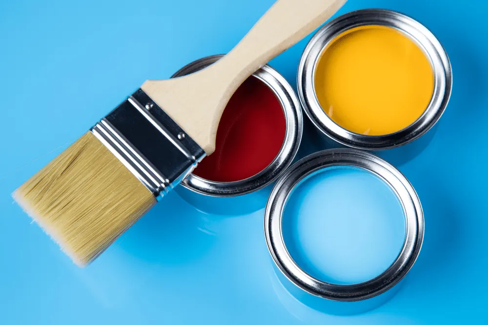 Three cans of paint with a brush on a top.