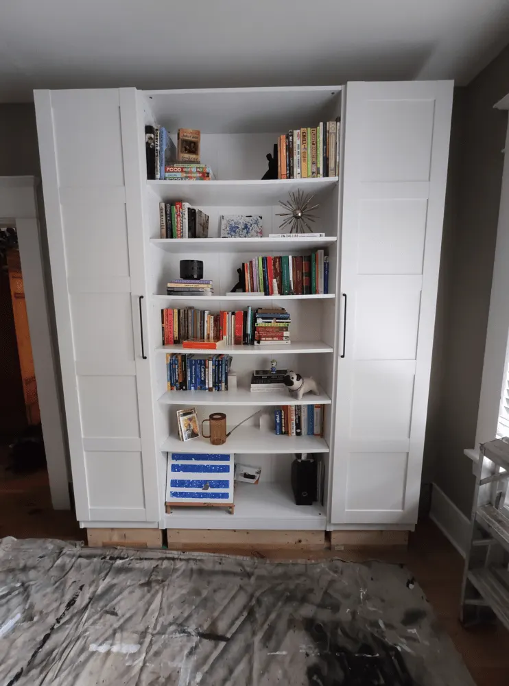 White bookshelf with doors, filled with colorful books; client finds top and bottom parts less appealing.