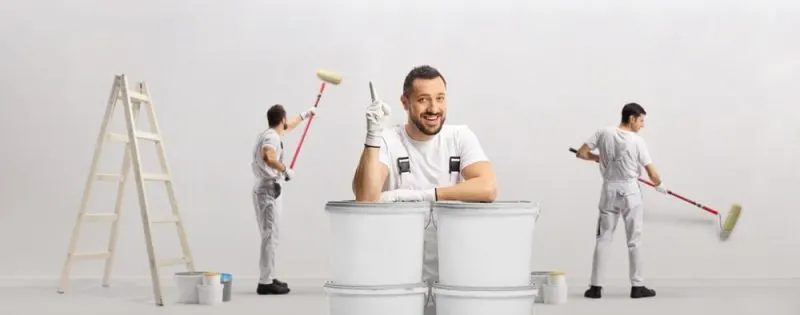 A painter has an idea while 2 painters are working in the background.