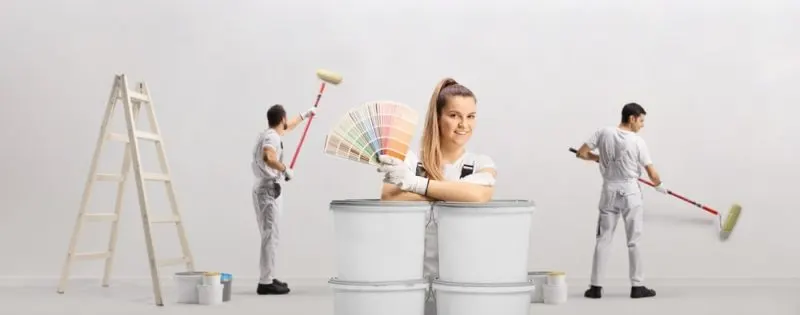 A woman is showing colour chips with 2 contractors in a background.