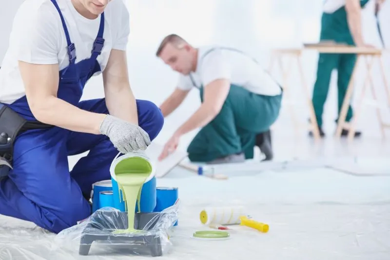 Painters are at work pouring paint in the tray.