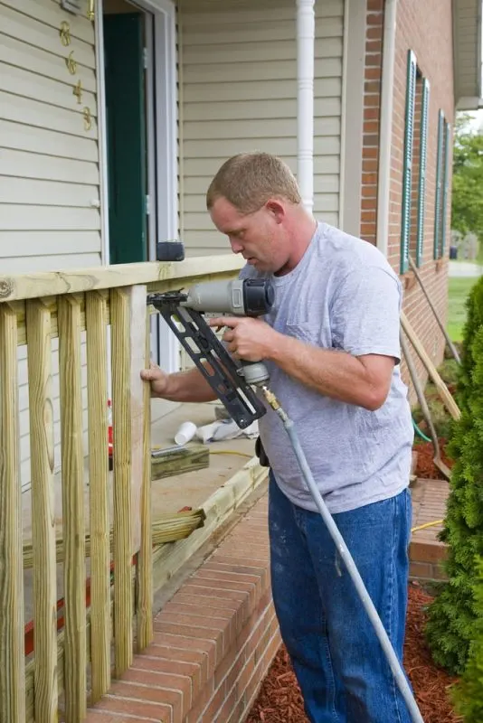A contractor is using a nail gun to fix exterior rails.