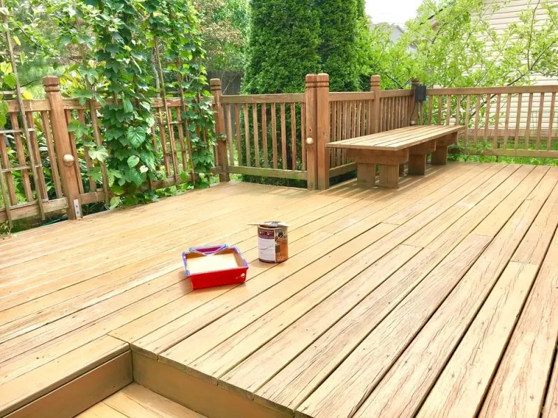A stained wooden deck with a can of paint and a tray.