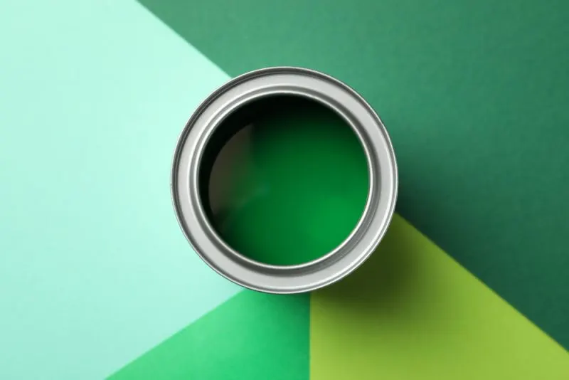 A can with a green paint on a green shaded floor.