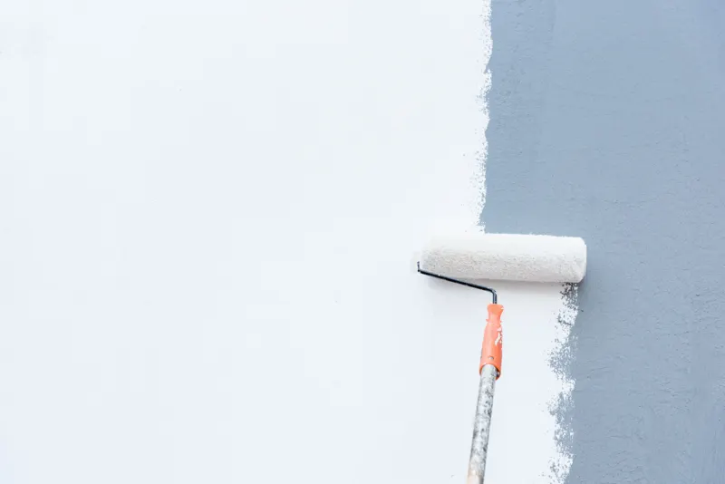 Paint a gray wall in a white colour with a roller