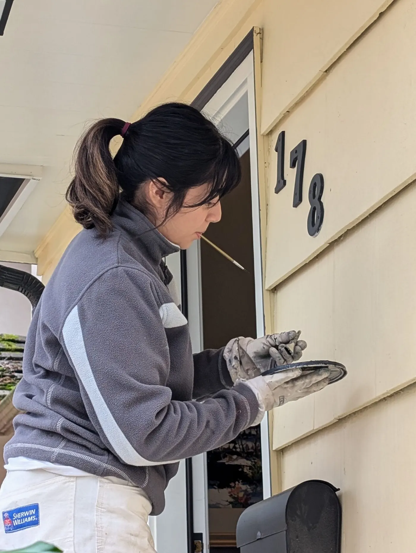 A painter is painting a house number with extra precision.
