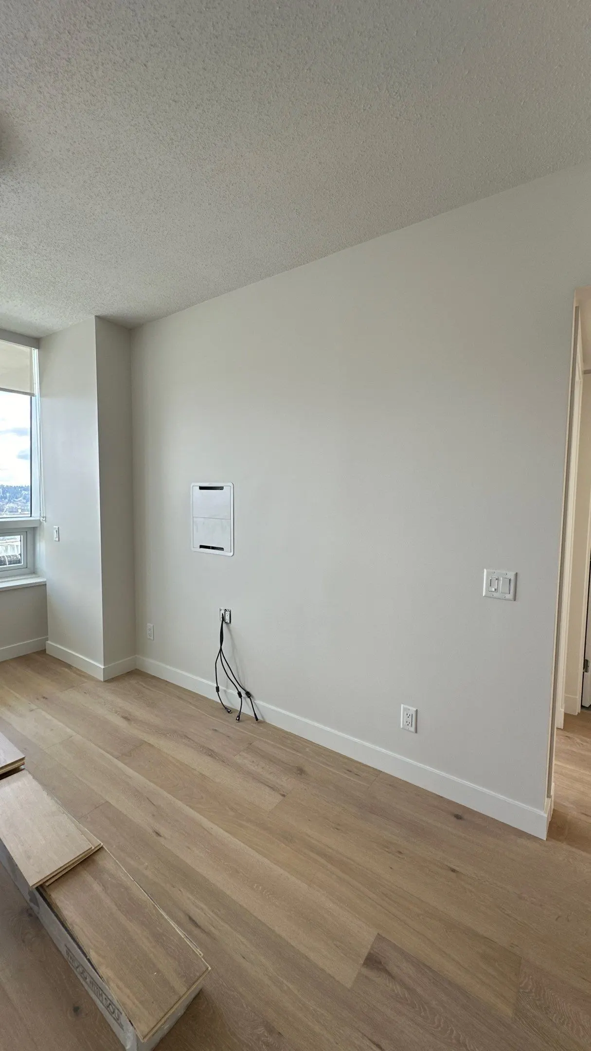 Newly painted white walls in a room with light wood flooring, ready for interior design or cabinet installation. Perfect for painting services.