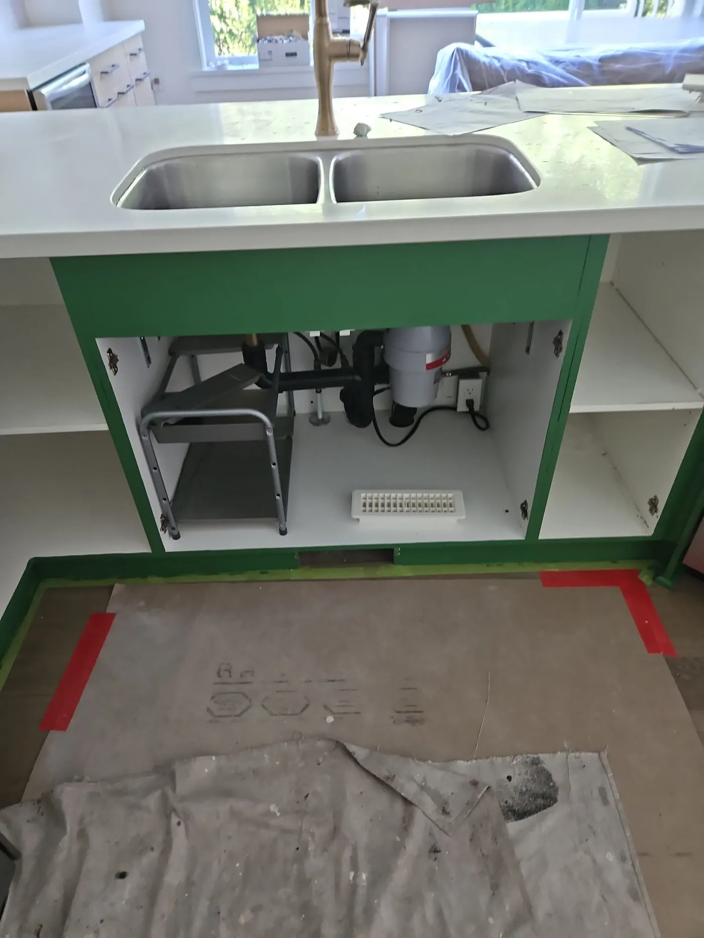 Spacious kitchen with professionally painted two-tone cabinets—white uppers and dark grey lowers—accented by a large island, hardwood floors, and modern lighting, ideal for cabinet refinishing.