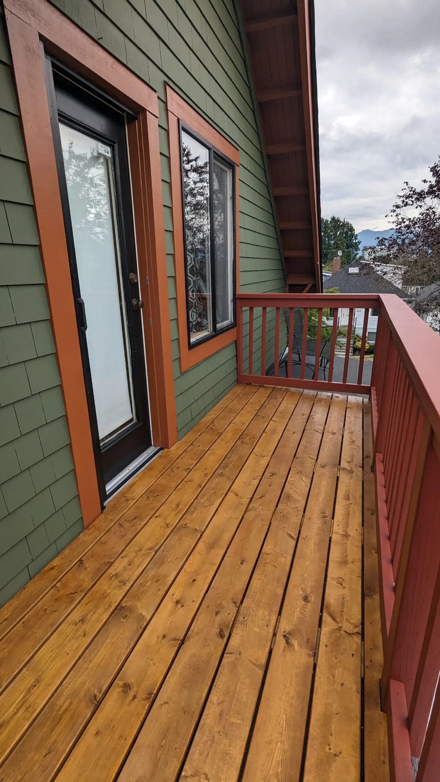 Wooden deck with red railing and house, custom deck repair