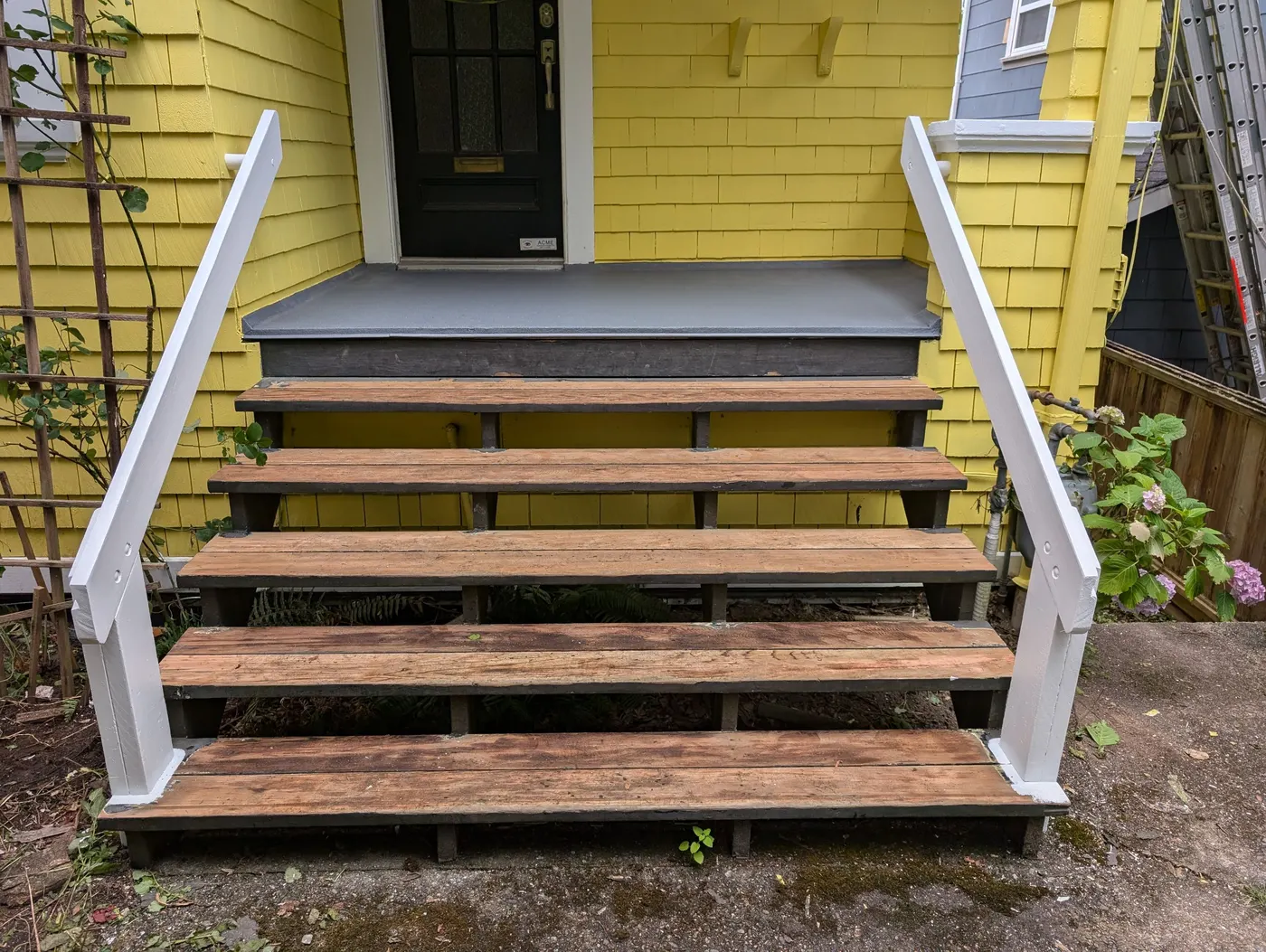 Freshly painted bright yellow cedar shingle siding surrounding a white-framed sliding patio door on a Vancouver home's back porch.