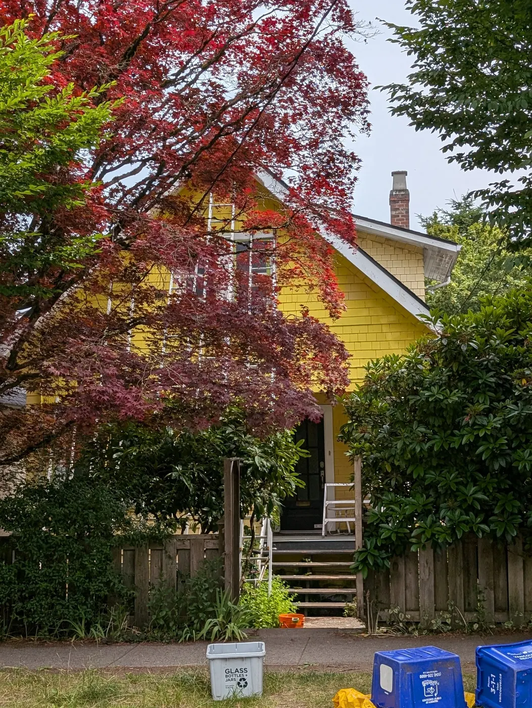 Newly resurfaced wooden front steps with fresh white railings leading up to a bright yellow painted porch on a Vancouver, BC home.