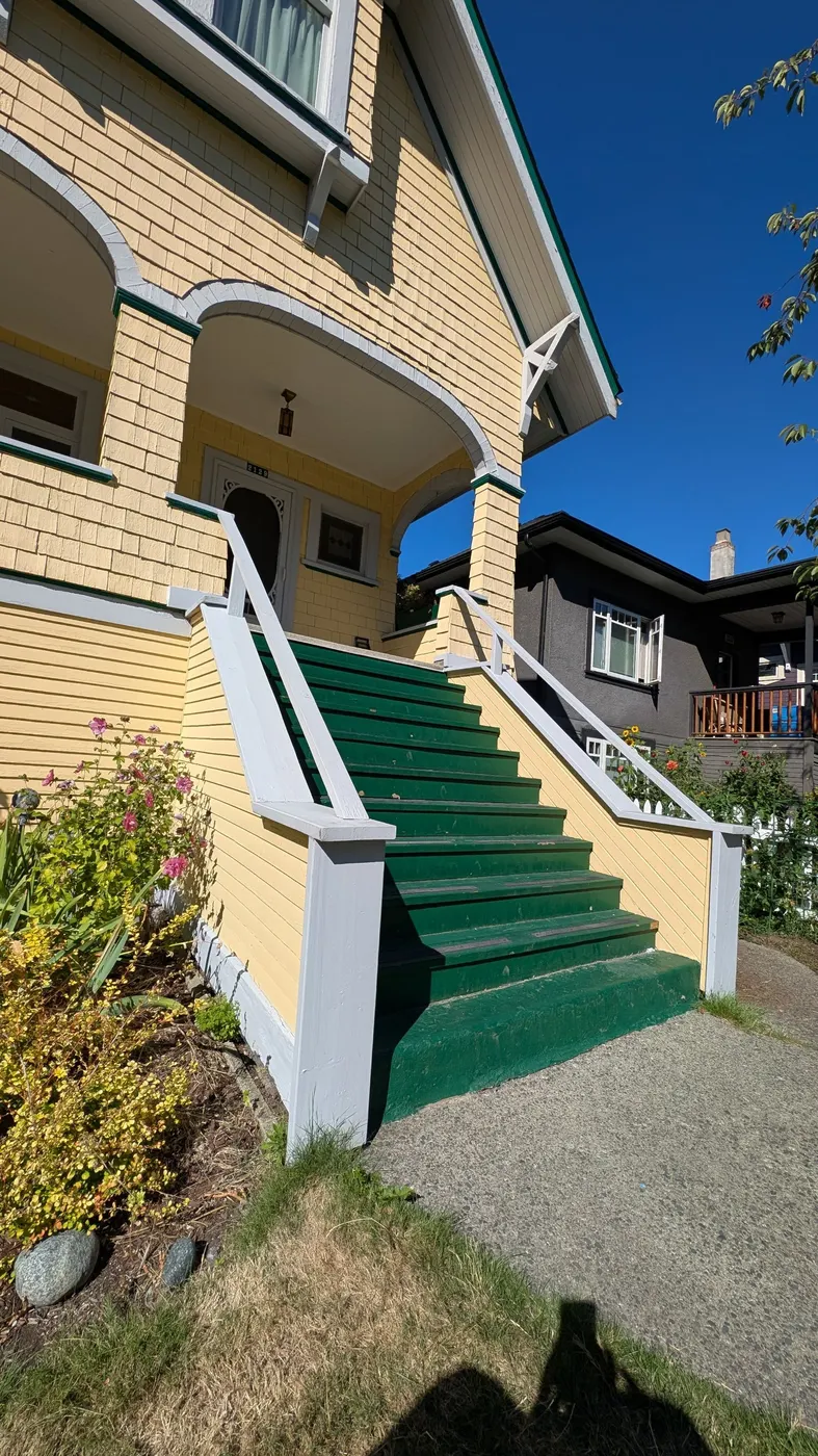 Worn wood exterior staircase with peeling green steps on a Vancouver character home, before Renaissance Painting's stair rebuild