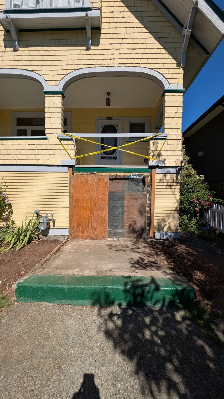 Demolished wood staircase area with the entry landing removed and boarded up, mid-renovation on a Vancouver Craftsman home
