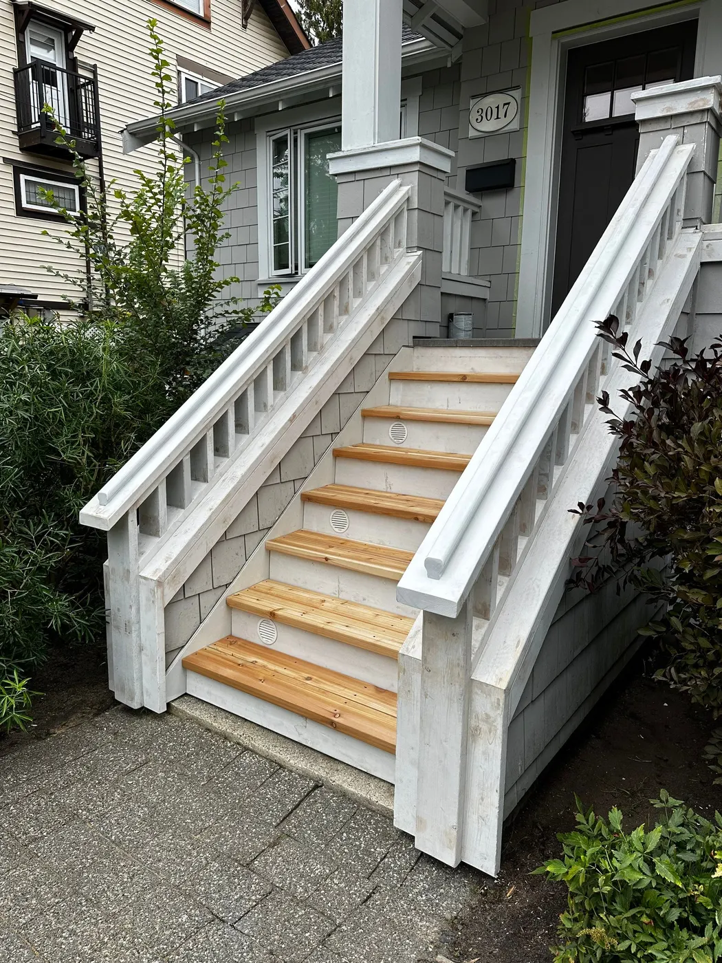 Finished front entry staircase in Vancouver, BC featuring new natural cedar treads and freshly painted white risers and railings.