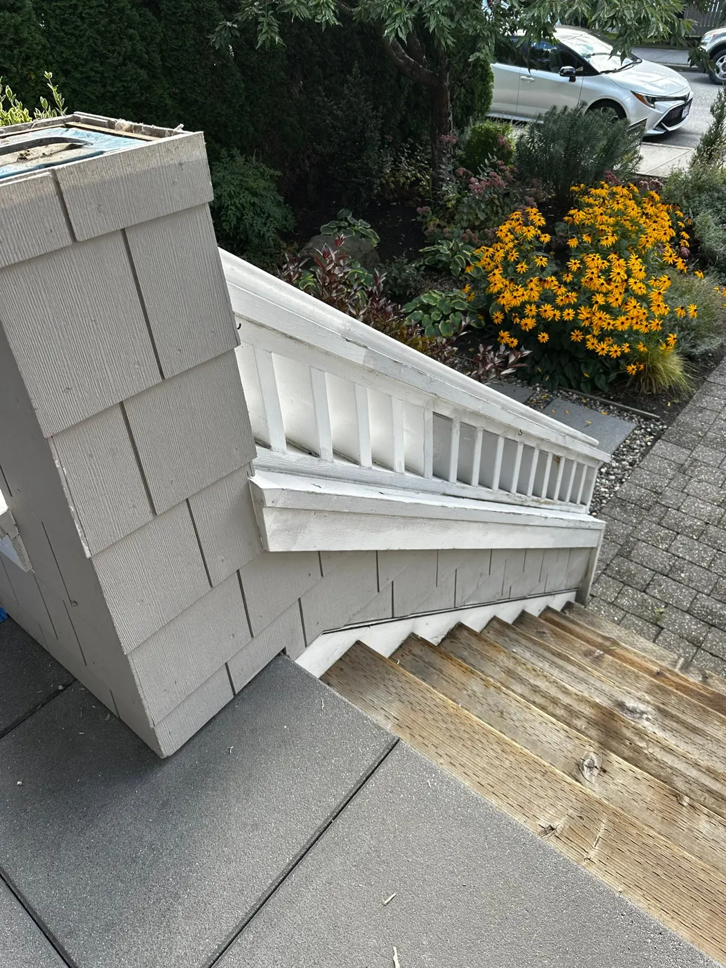 Worn, peeling white-painted wood stair railing and unfinished treads on a Vancouver, BC home before carpentry and painting restoration.