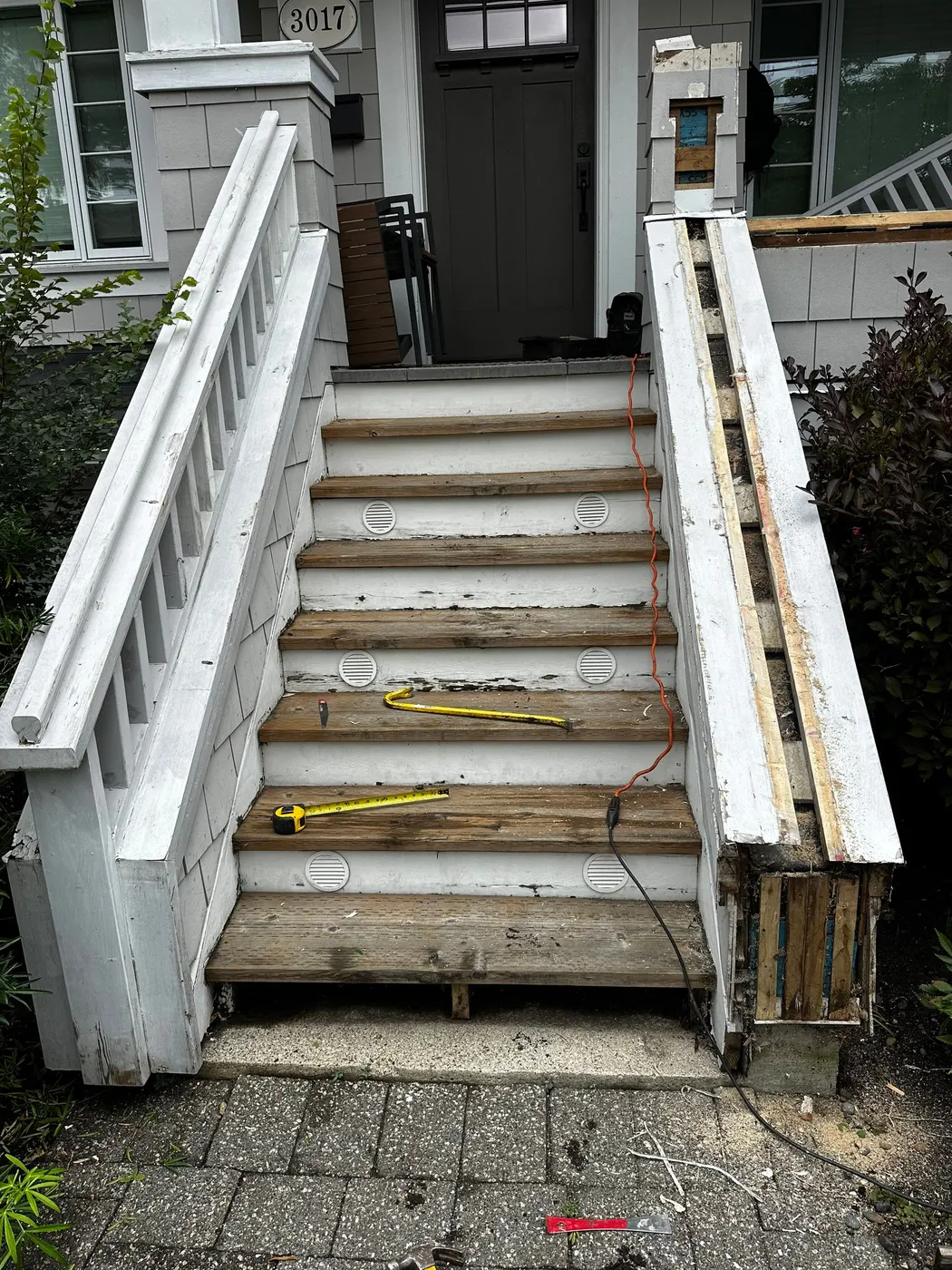 Close view of cracked, weathered wooden stair treads on a Vancouver home's front entry staircase during renovation prep.