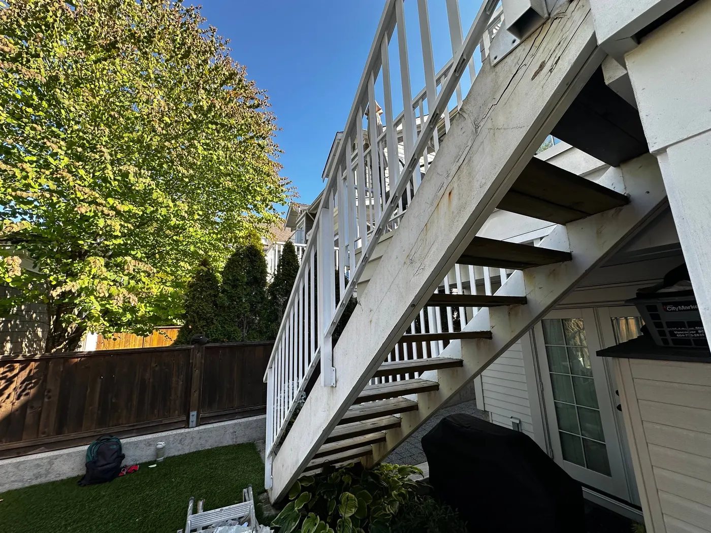 Weathered grey wood stairs and railing on the rear deck of a Vancouver, BC home before painting and carpentry restoration.