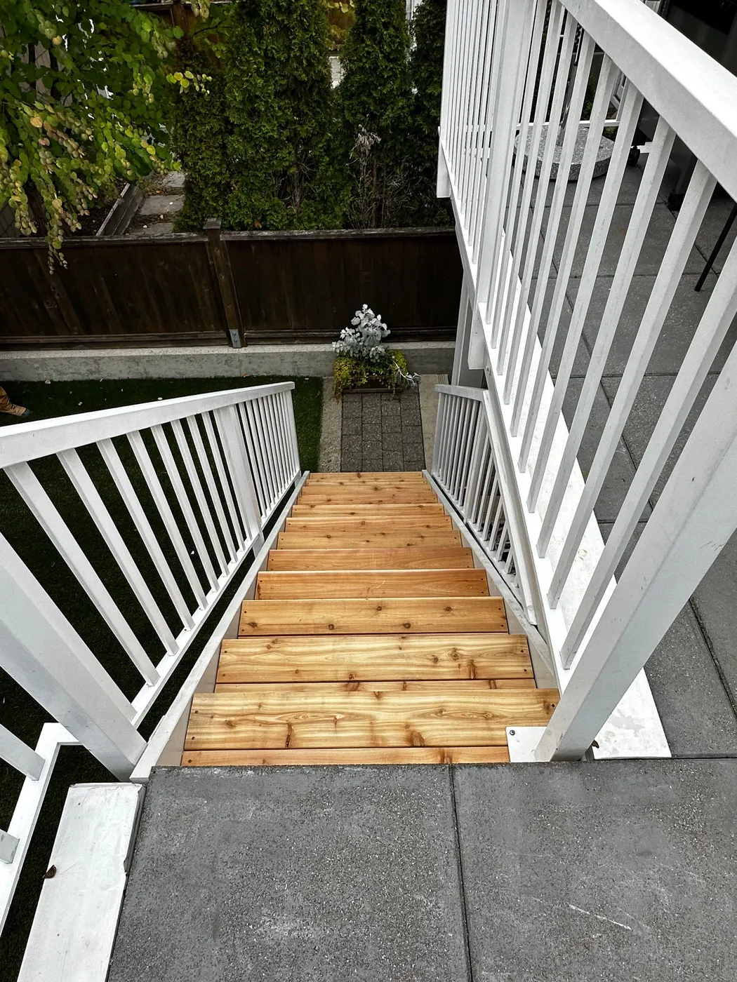 Top-down view of freshly installed natural cedar stair treads and white railings on a rebuilt rear staircase in Vancouver, BC.