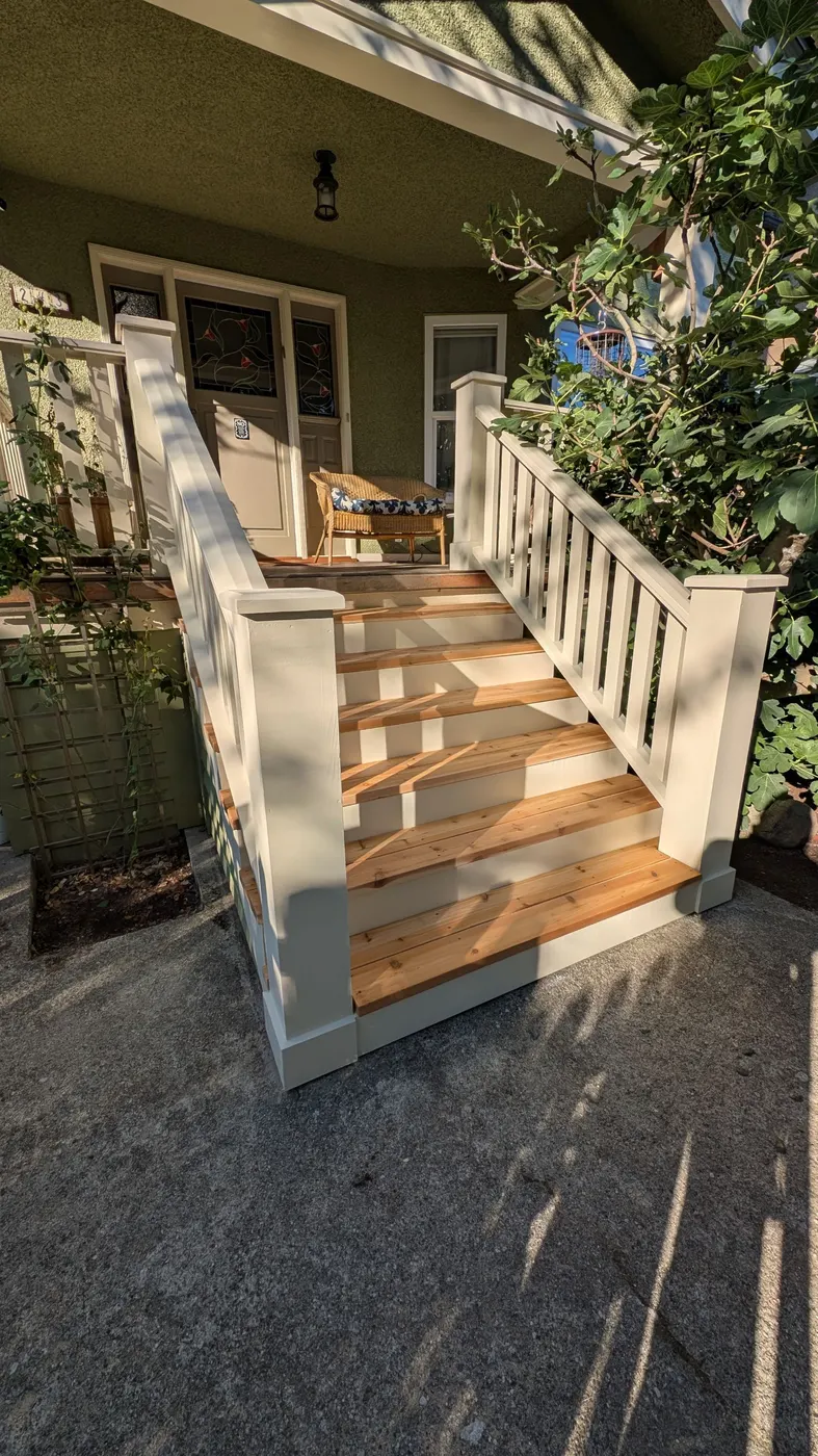 Finished front porch stairs with new cedar treads and crisp white painted railings on a Vancouver craftsman home.