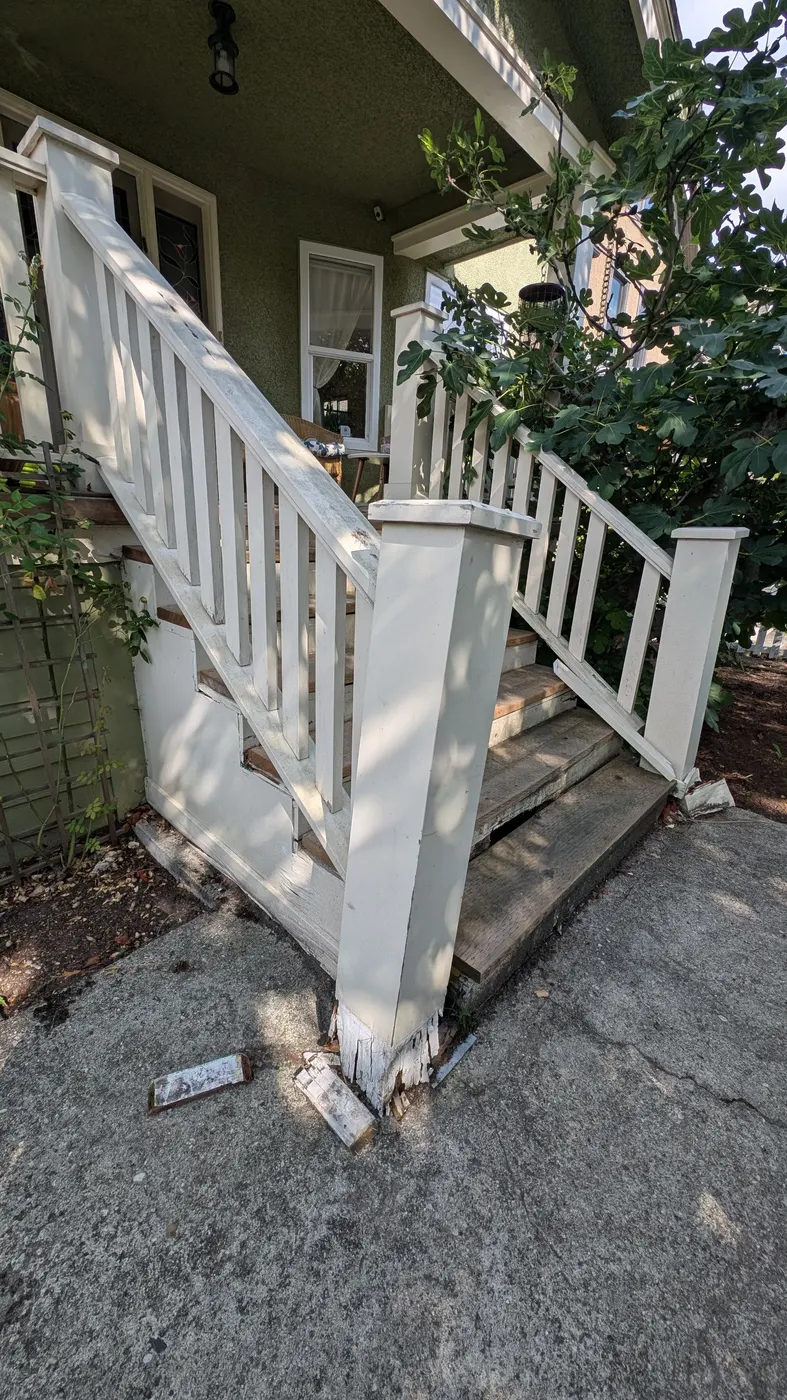 Close-up of a severely rotted porch post base crumbling apart on a Vancouver, BC home, showing extensive wood decay before restoration.