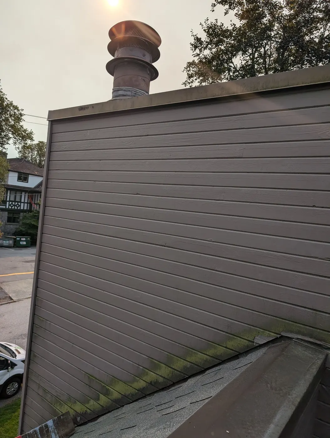 Upward view of a repainted chimney and roofline siding on a Vancouver, BC house exterior.