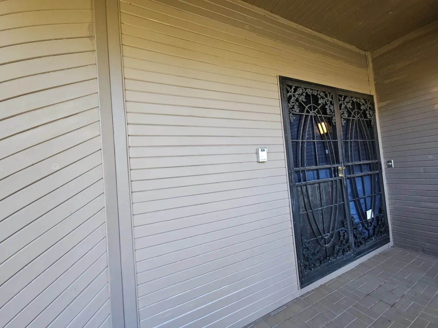 Close-up of a freshly painted covered porch and wrought-iron security door at a Vancouver, BC home exterior.