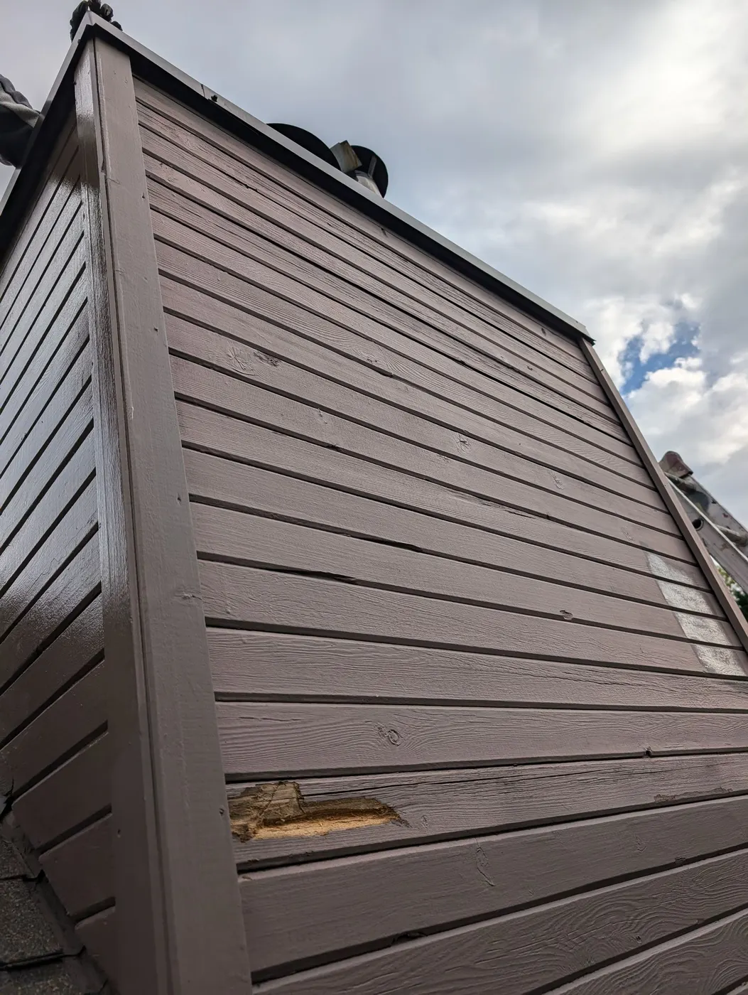Newly painted dormer siding in a rich brown tone against the sky, on a Vancouver, BC home exterior.