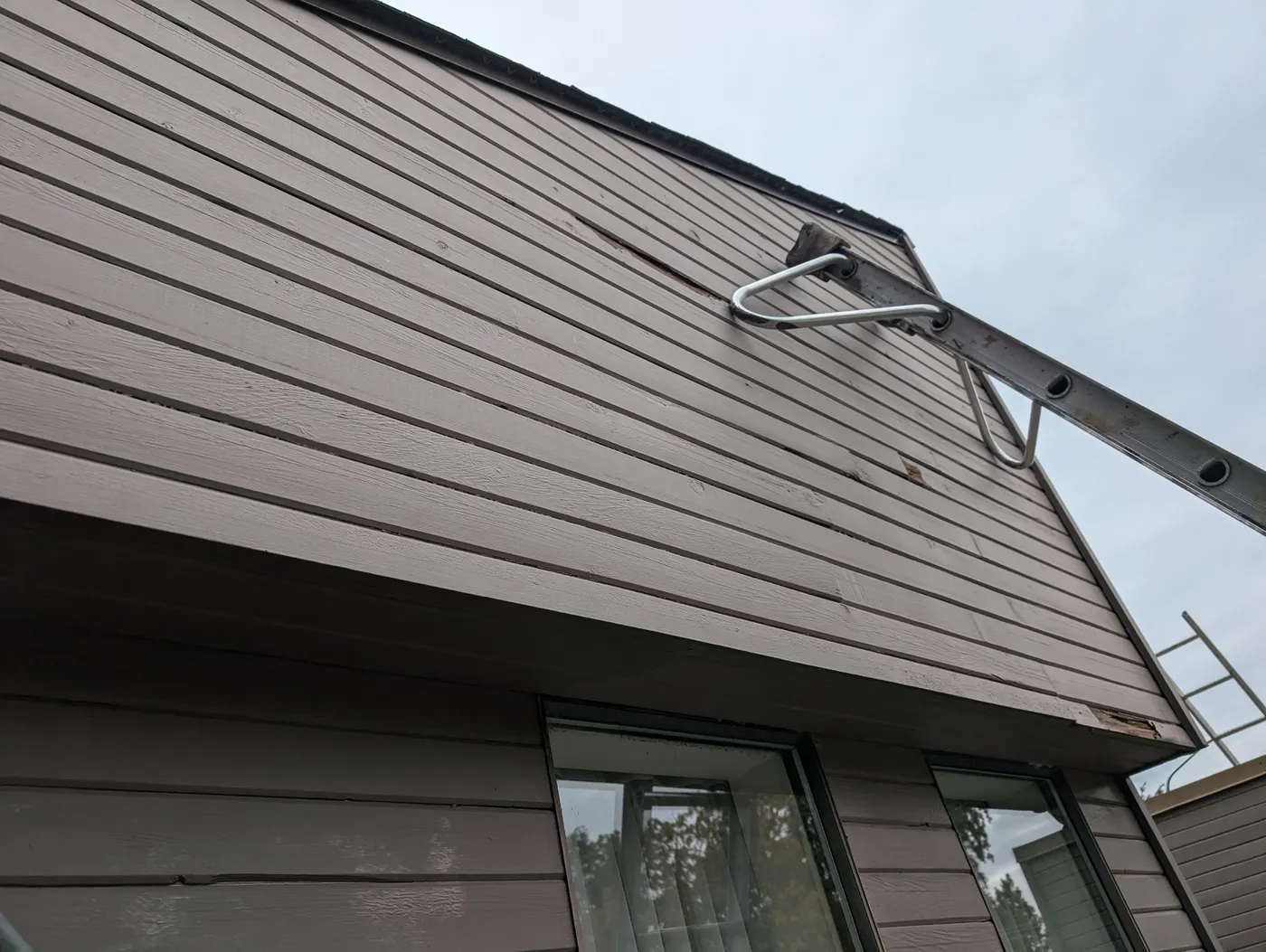 Freshly painted light taupe siding on a gable end of a Vancouver, BC home, viewed from below.
