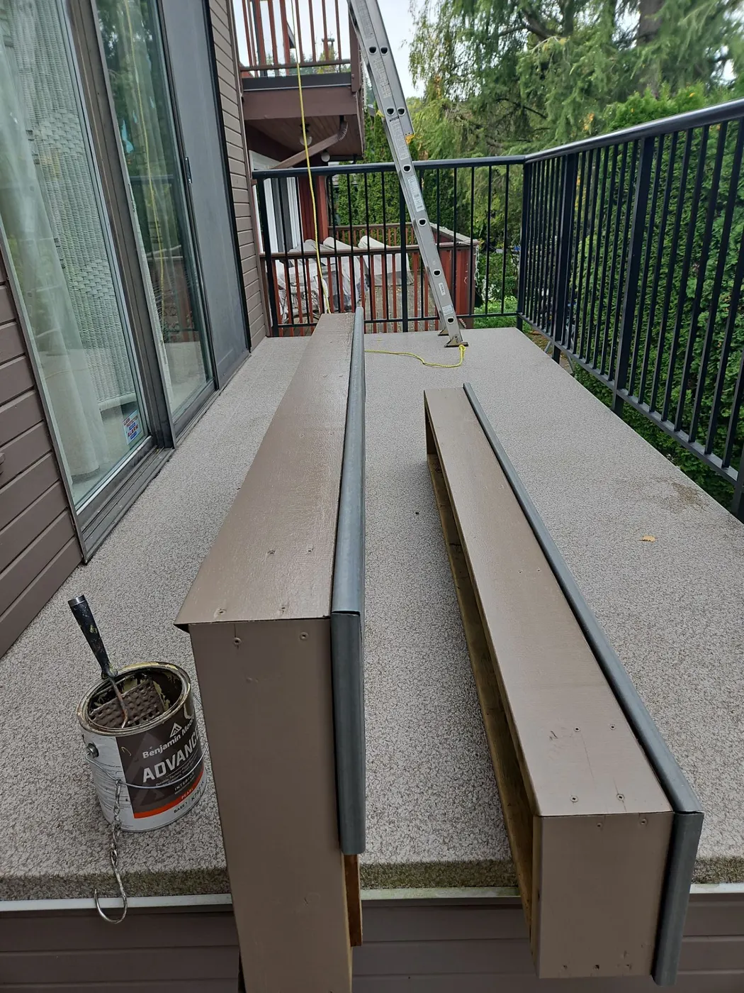 Open can of Benjamin Moore paint beside freshly painted trim boards on a Vancouver, BC deck.