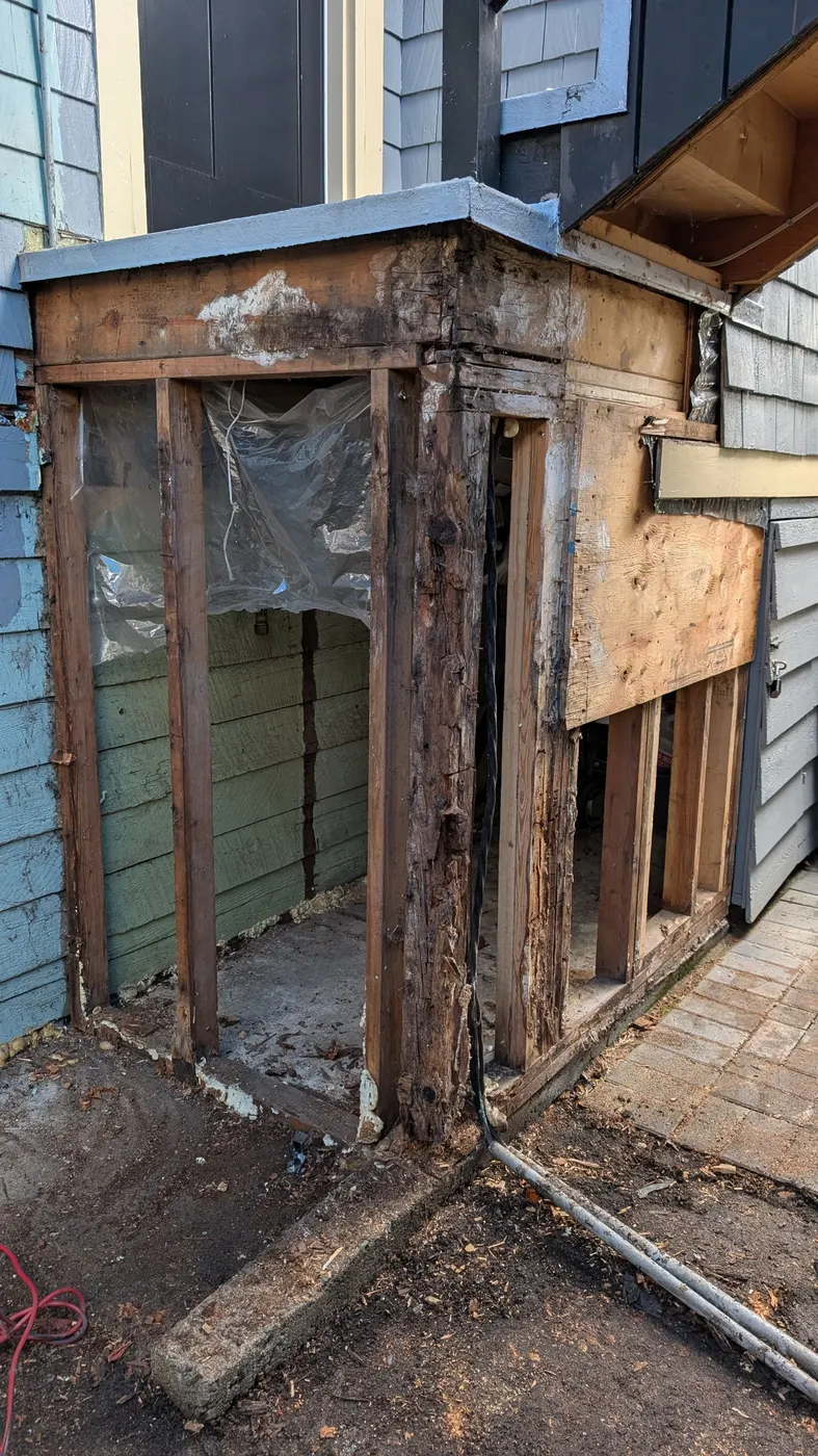 Open wall cavity with rotted wood framing exposed during a carpentry rebuild on a Vancouver, BC home