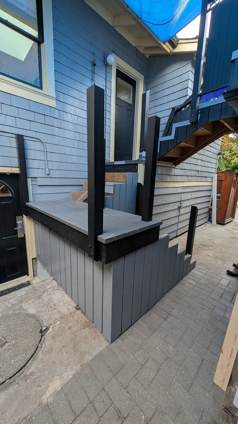 Finished elevated wood deck with black trim and railings outside the back entrance of a Vancouver, BC home