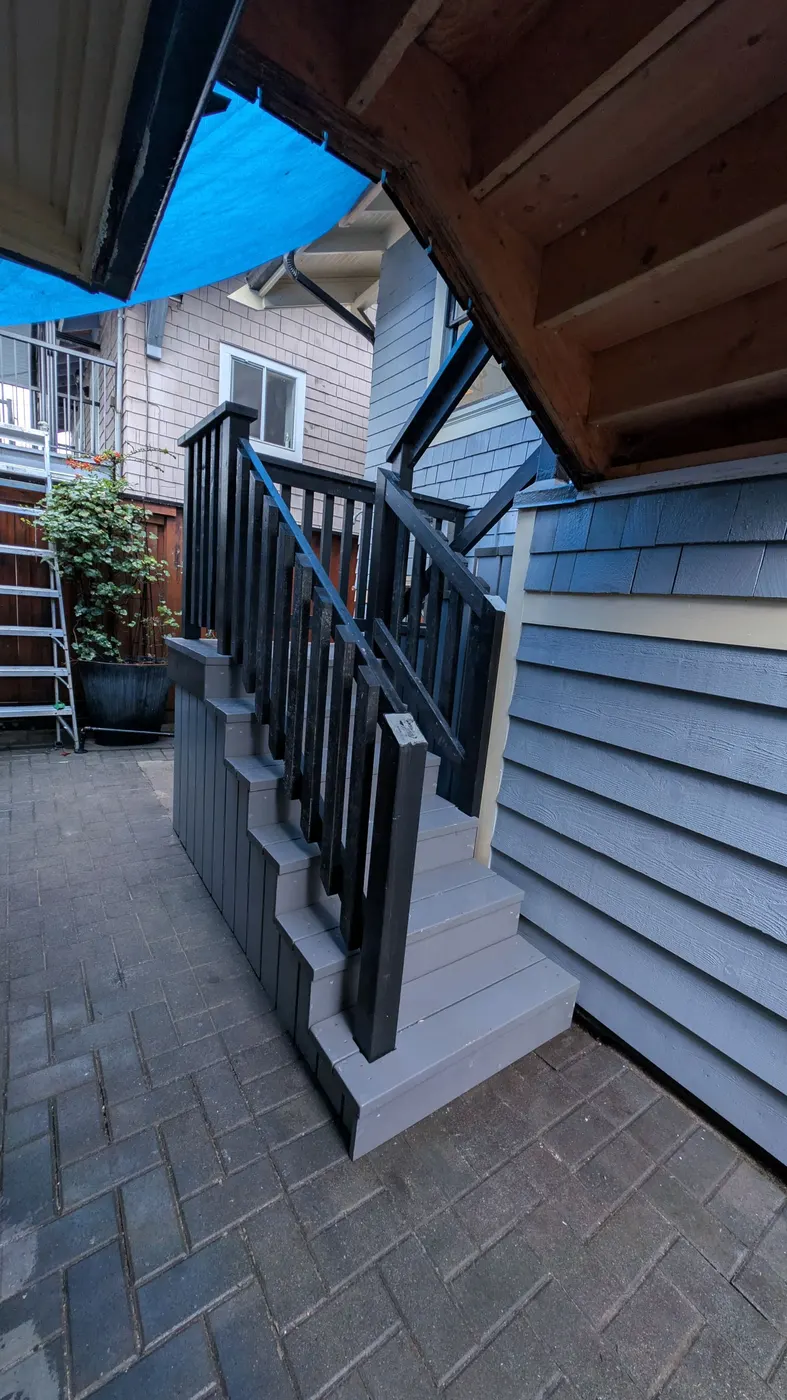 Completed exterior wood staircase with black railings and gray steps at a Vancouver, BC residence
