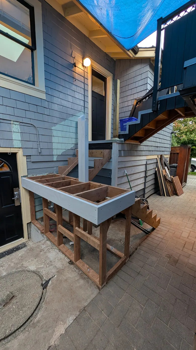 New black porch support posts being installed above a partially built deck frame on a Vancouver, BC home