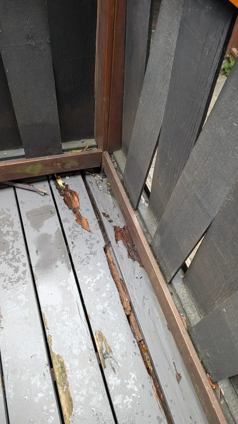 Rotted deck boards and decayed trim at a back door threshold on a Vancouver home before carpentry repair