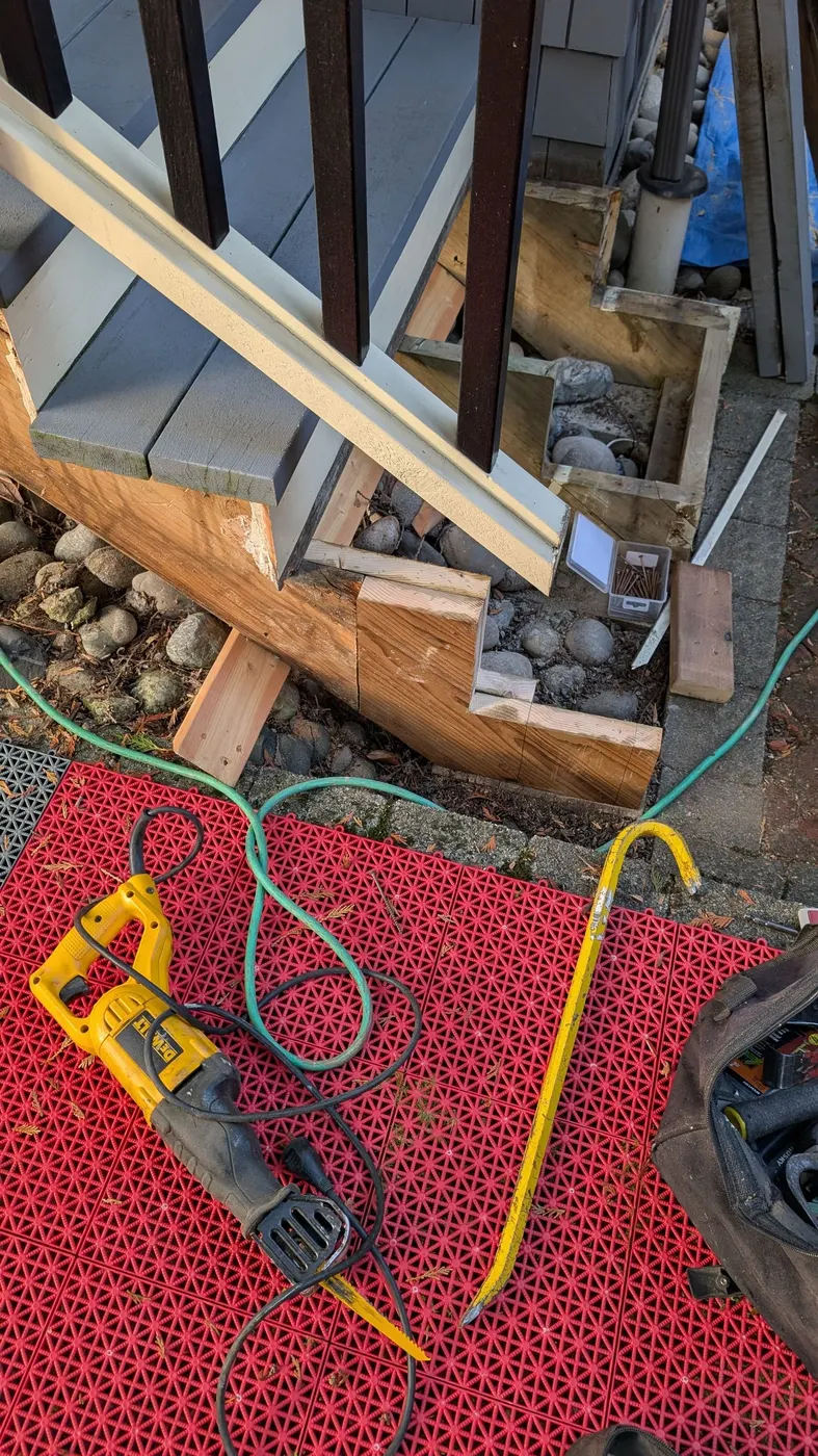 Detail of new wood joinery and sistered framing repair at the base of an exterior stair post, Vancouver BC carpentry work.