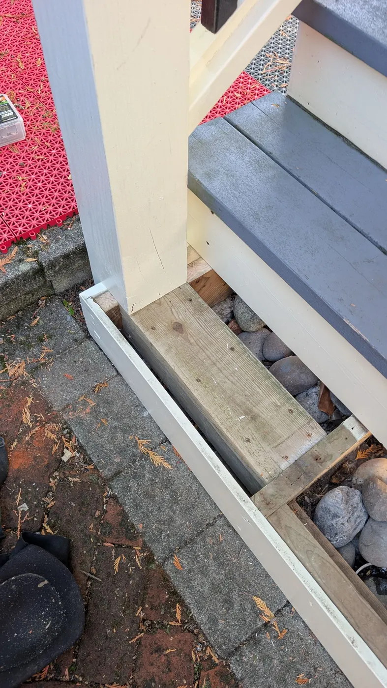 Close-up of new wood trim seamlessly repaired and blended at the base of a painted exterior stair post in Vancouver, BC.