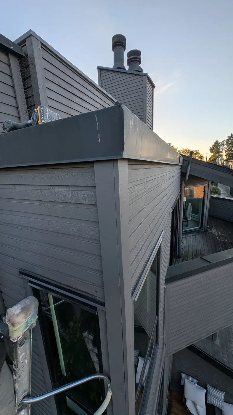 Freshly repaired and painted grey wood siding on a strata building corner in Vancouver, BC at dusk.