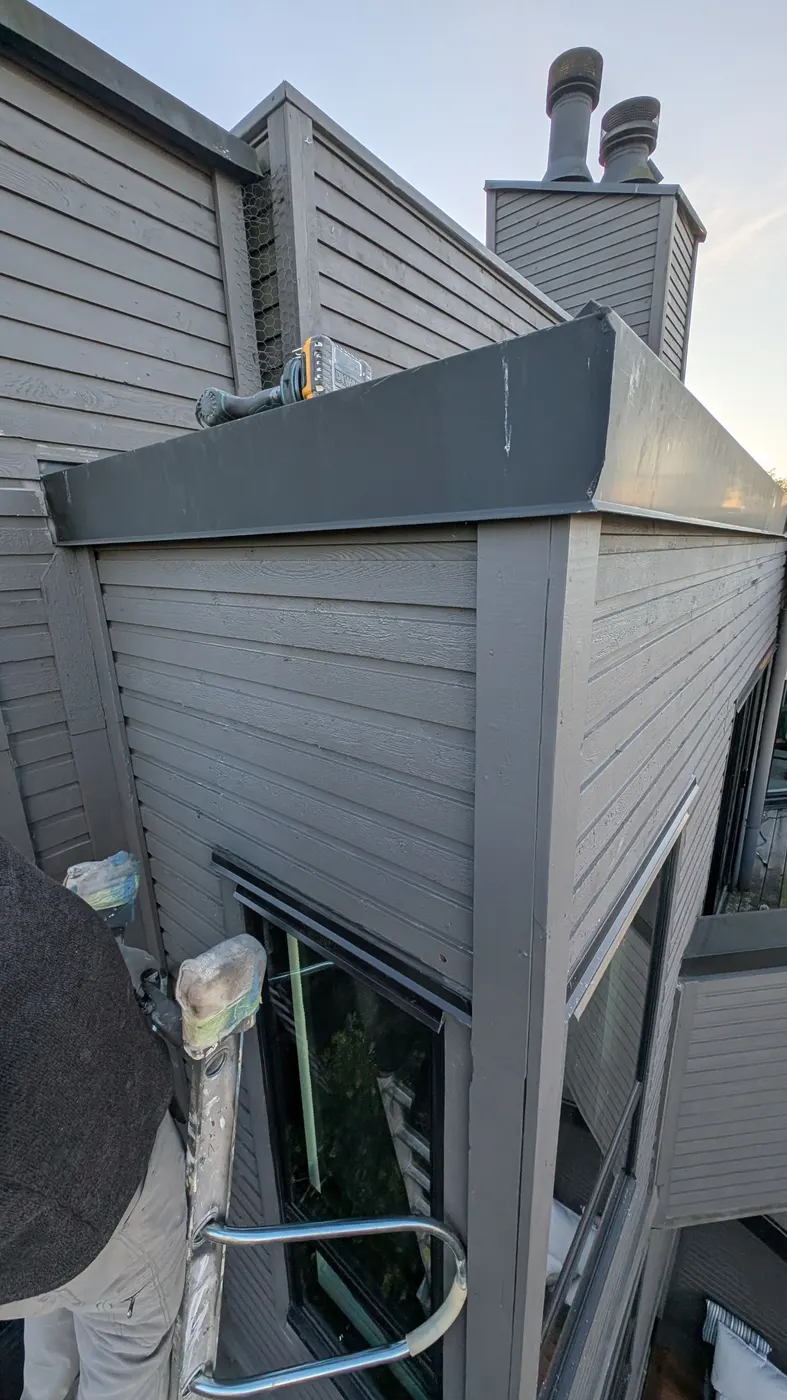 Wide view of the completed grey wood siding repair on a Vancouver strata building corner at sunset.