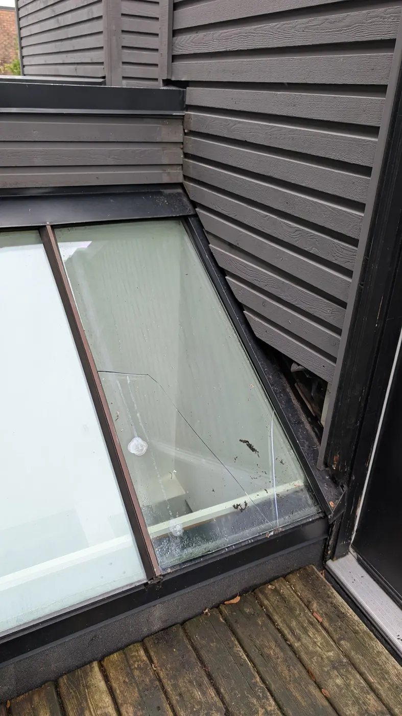 Close-up of a cracked skylight glass panel found during a carpentry assessment at a Vancouver, BC home, showing spider-web fracture damage.