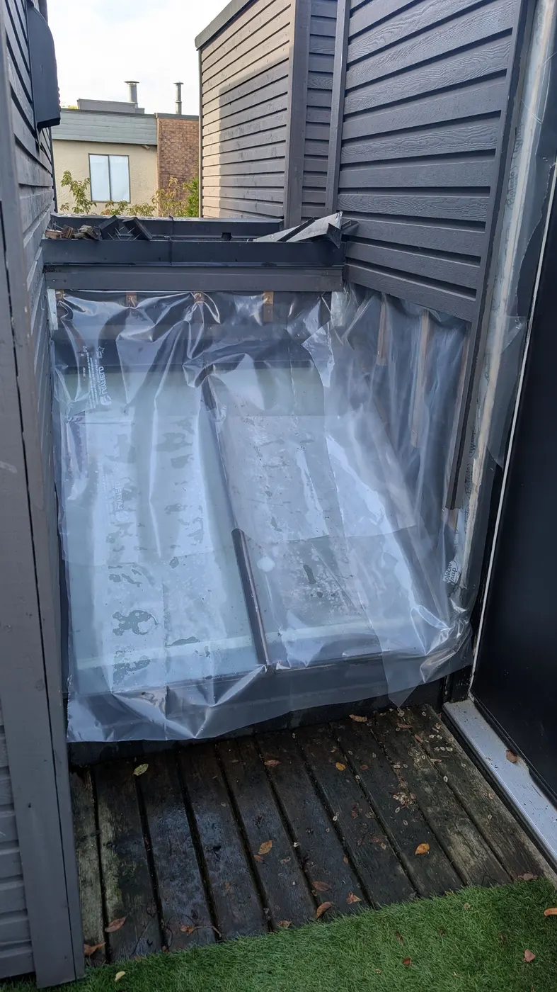Clear plastic sheeting installed over an open skylight well to weatherproof the area during an ongoing carpentry repair at a Vancouver, BC home.
