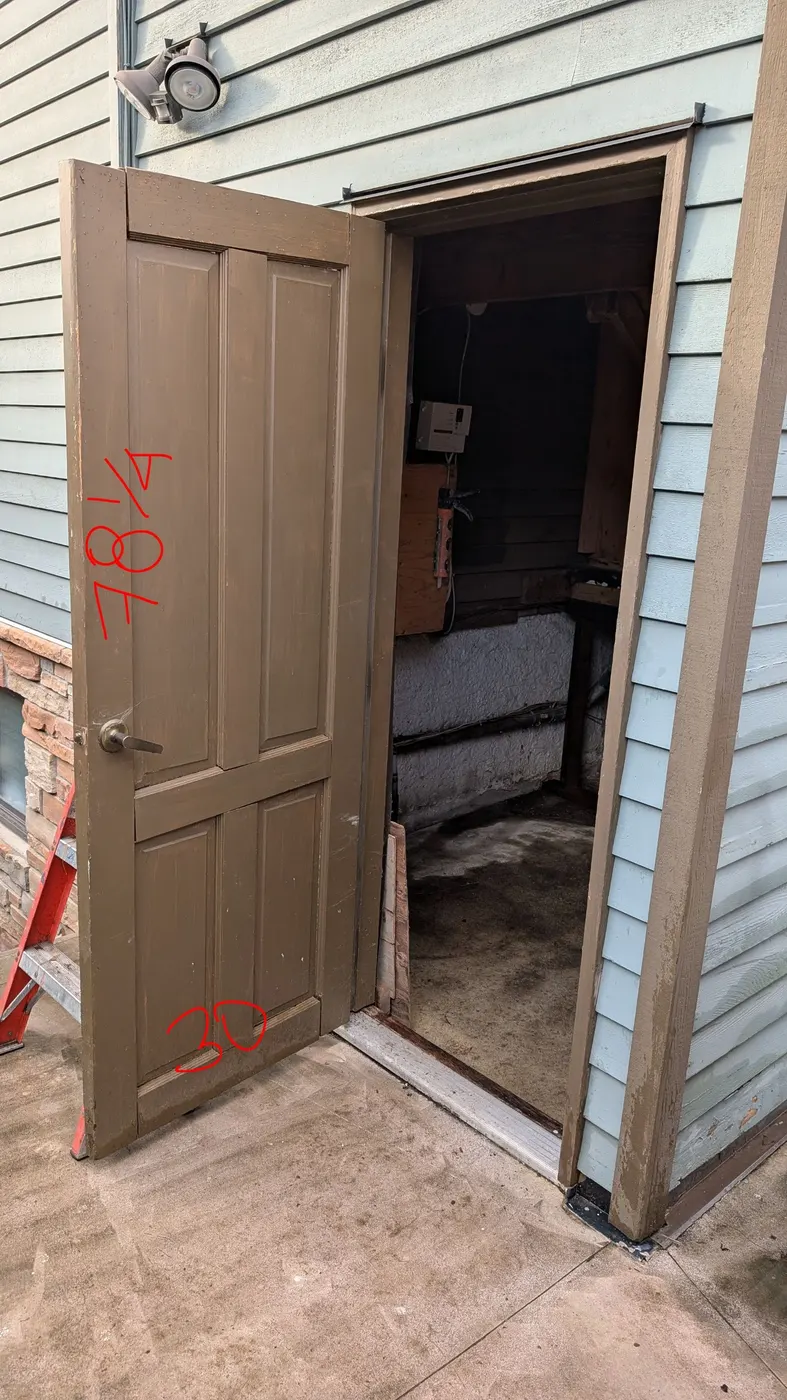 Open crawlspace access door with contractor measurements marked in red during a Vancouver, BC carpentry assessment.