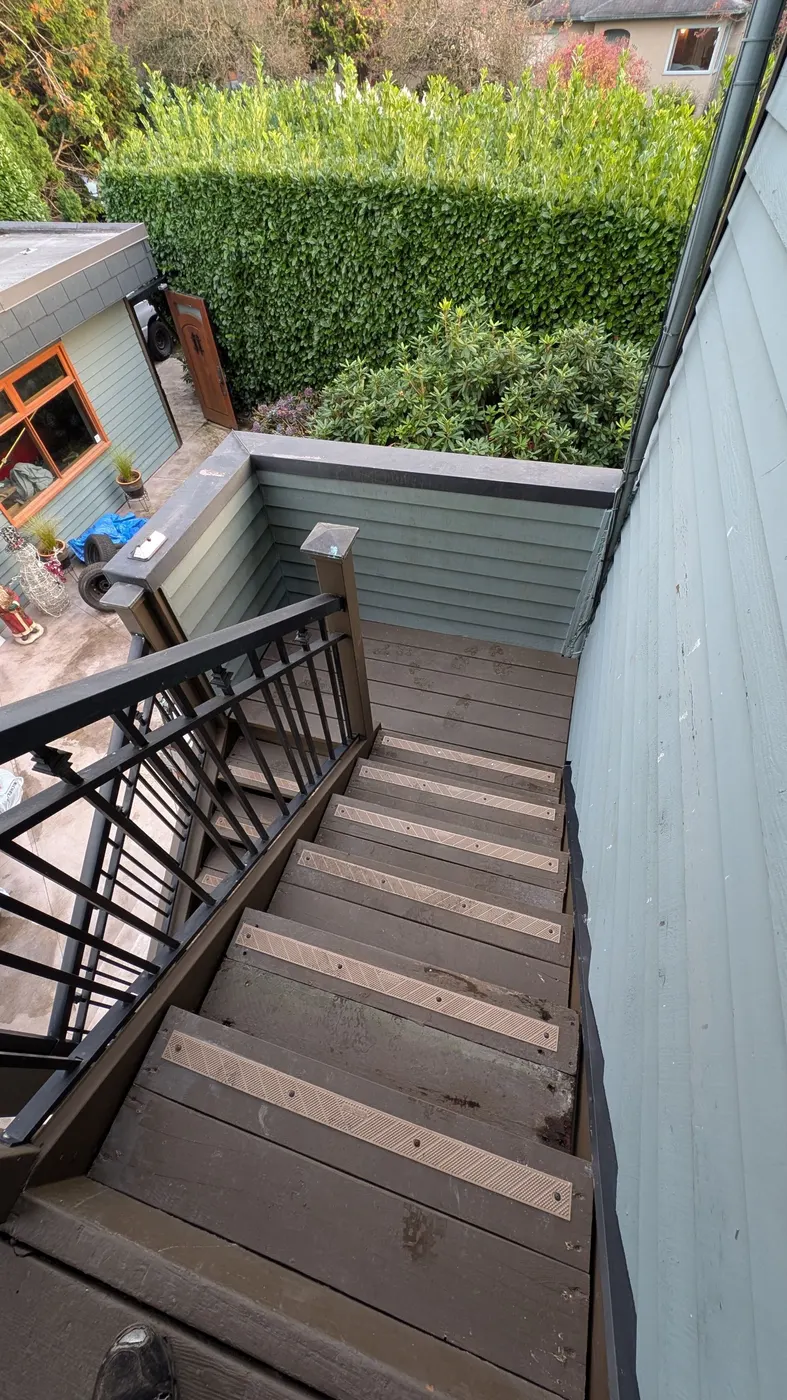 Completed wooden deck stairs overlooking a landscaped backyard in Vancouver, BC after carpentry renovation.