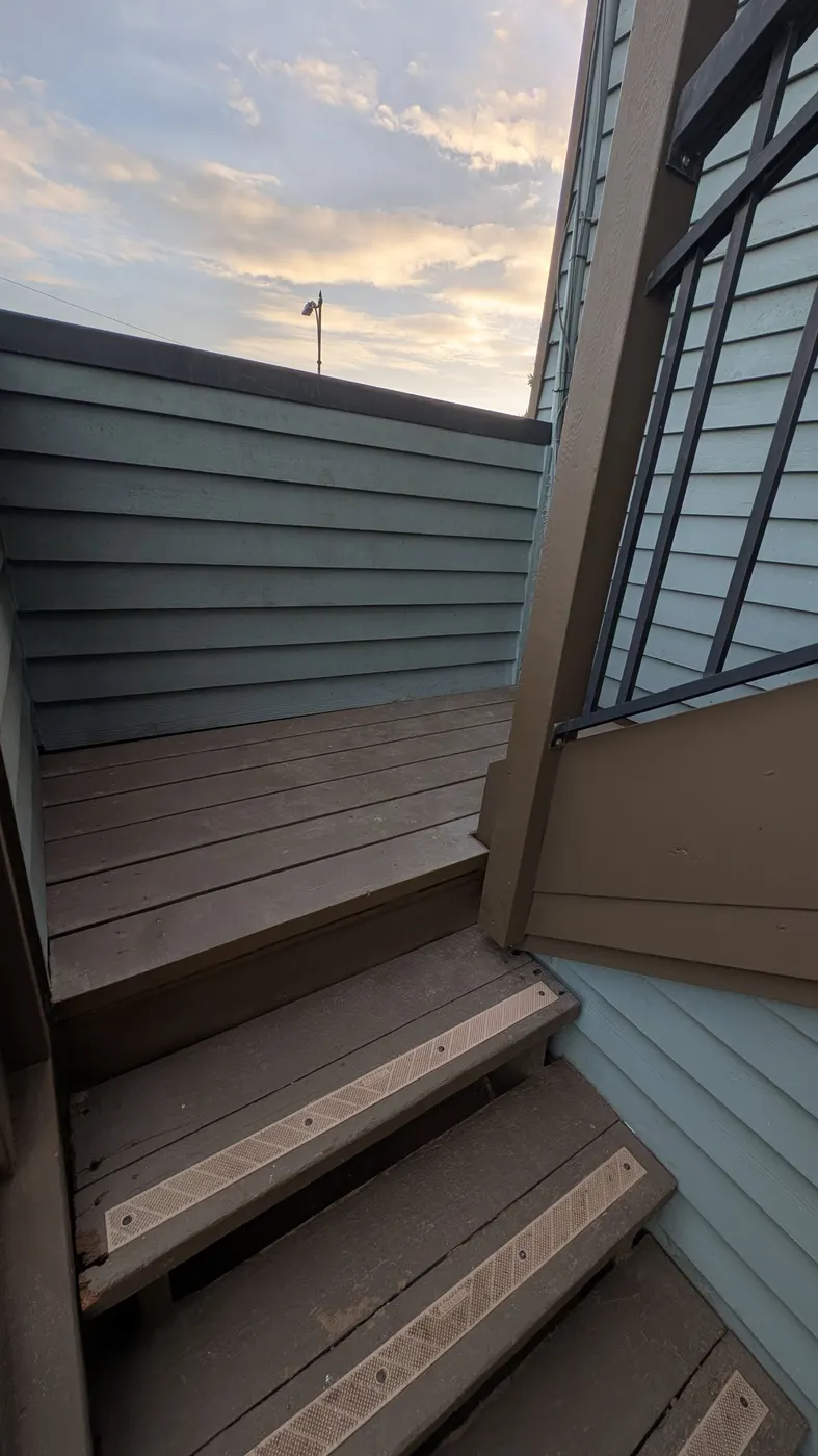Newly rebuilt wooden exterior stairs leading down between two homes in Vancouver, BC at dusk.