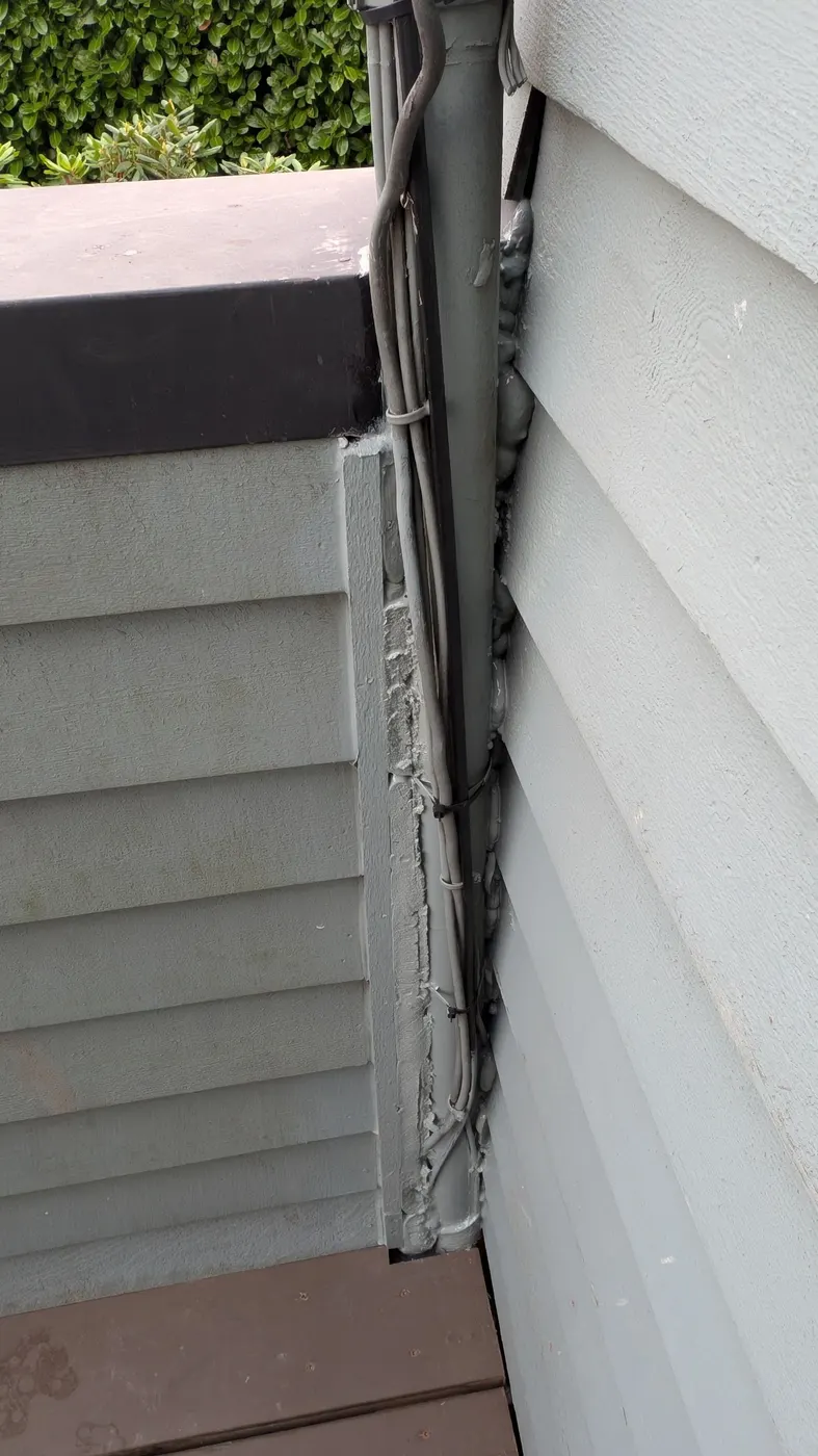 Close-up of a newly sealed gutter downspout and trim corner on a Vancouver, BC home exterior.